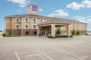 A Sleep Inn & Suites building with a covered entrance, a parking lot, and a clear sky. - Sleep Inn & Suites Idaho Falls Gateway To Yellowstone (Idaho Falls)