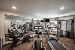 Un gimnasio con cintas de correr, elípticas y pesas sueltas.