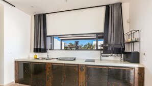 A modern kitchen with a large window, a sink, and a countertop with a laptop and a kettle. - Villa Aspri Luxury by Perle di Puglia (Carovigno)