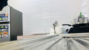Una cucina dotata di frigorifero, fornello e diversi utensili.