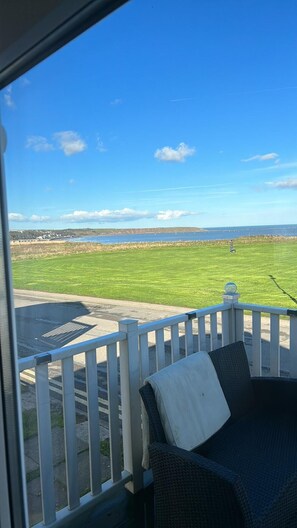 A balcony with a view of a grassy field and a body of water. - Apartment Sleeps 8 With Parking (Filey)