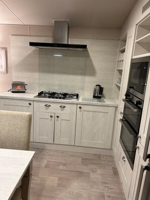 A modern kitchen with a gas stove, a toaster, and a coffee maker. - Apartment Sleeps 8 With Parking (Filey)