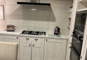 A kitchen with a gas stove, a toaster, a kettle, and a built-in oven.