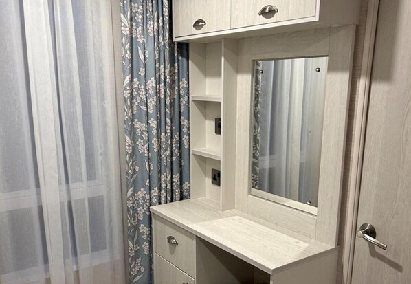 A bathroom vanity with a mirror, a light switch, and a door.