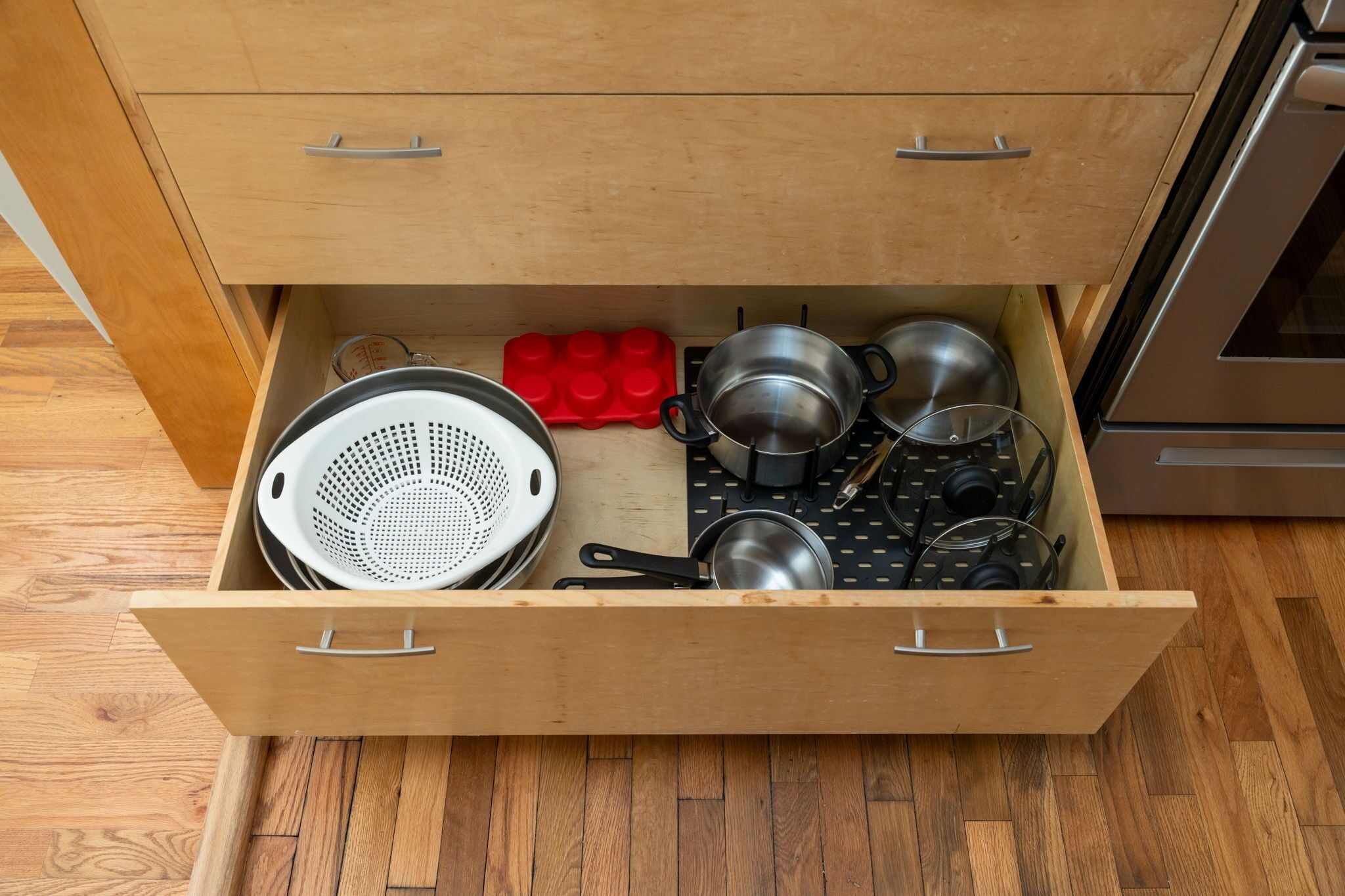A kitchen drawer with various utensils and cookware.