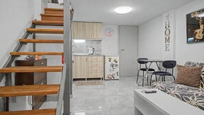 Un appartement moderne doté d’un escalier en bois, d’une cuisine avec des meubles en bois, d’un coin repas avec une table et des chaises, et d’un salon avec un canapé.