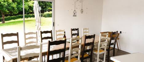 A dining area with a table and chairs, a view of greenery outside, and a decorative birdcage on the wall.