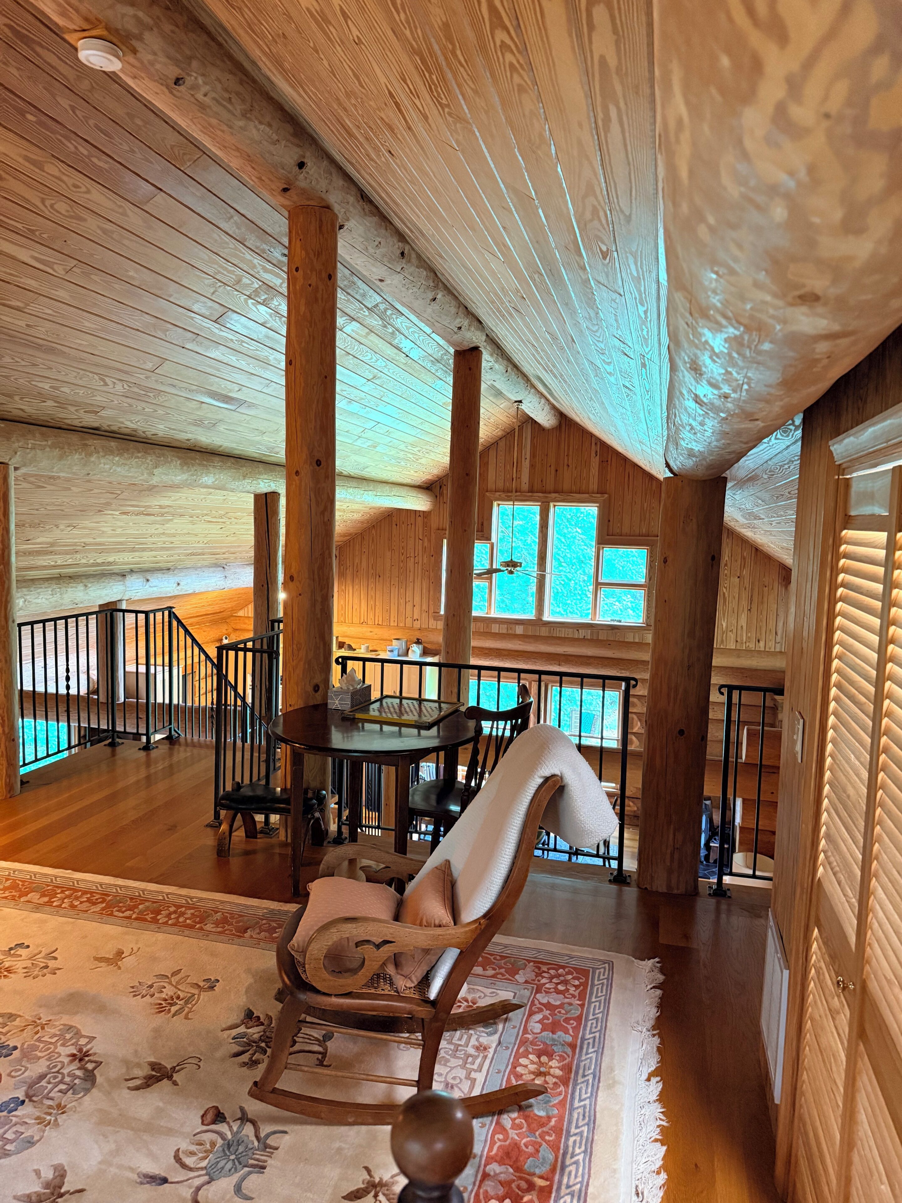 Un intérieur spacieux en bois, comprenant un coin repas, une grande fenêtre et un escalier.