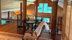 Un interior de madera espacioso con comedor, un ventanal grande y una escalera.