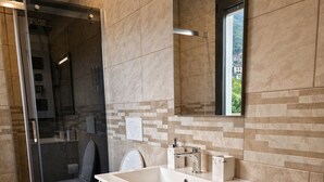 A modern bathroom with a glass shower enclosure, a toilet, a sink with a mirror, and a towel rack.
