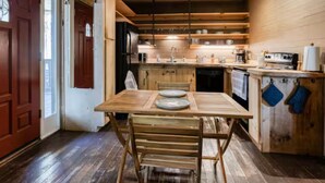A wooden interior with a dining table, chairs, a kitchen area with a sink and stove, and wooden floors. - Dreamy Mountaintop Escape for Two | Sauna & Views (Blue Ridge)