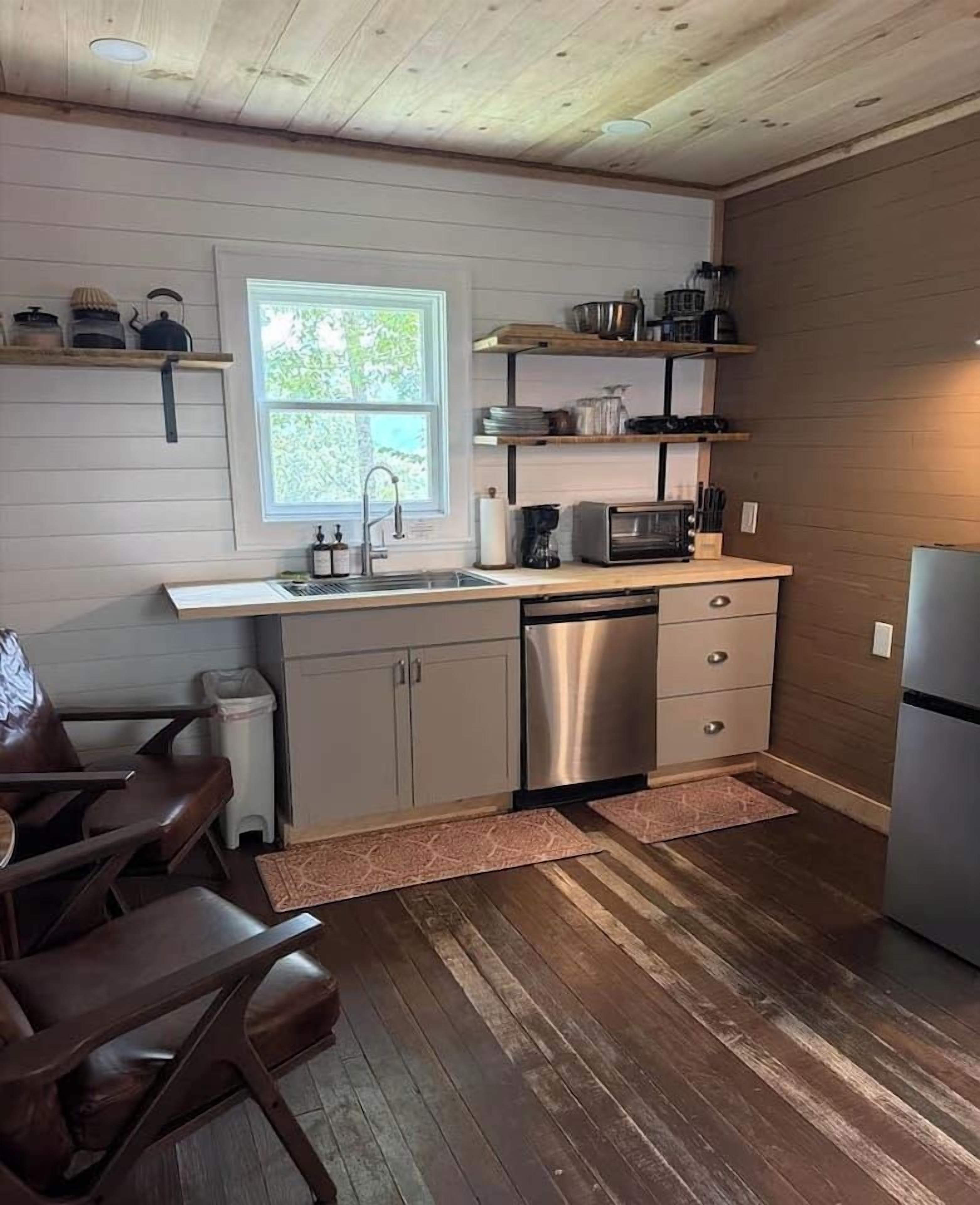 A compact kitchen with a sink, microwave, and stainless steel appliances.