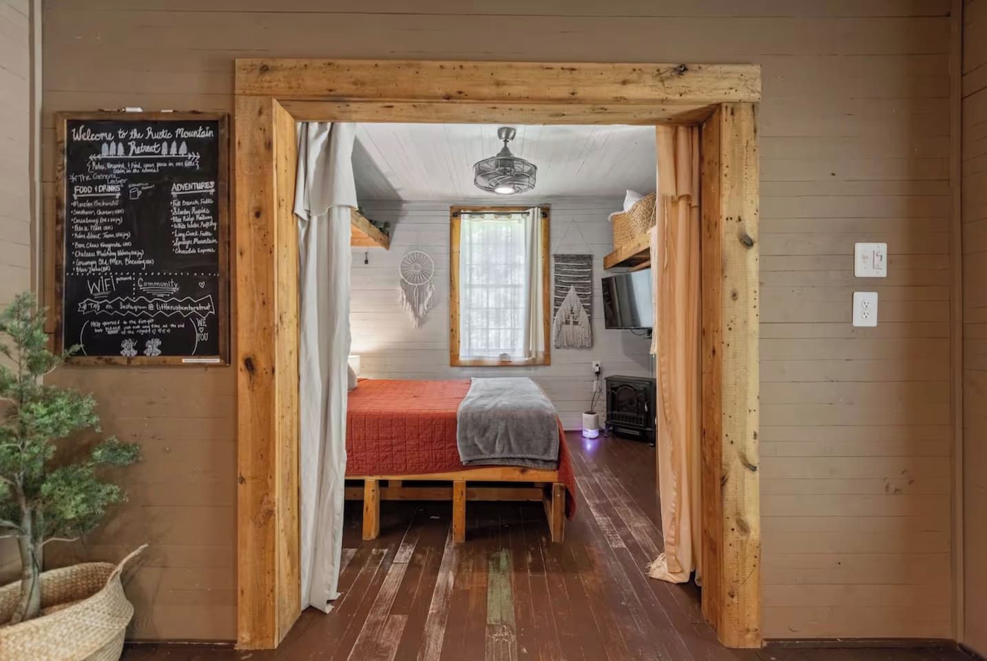 A rustic mountain retreat room with a bed, a window, a dreamcatcher, and a chalkboard menu.