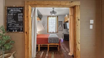 A rustic mountain retreat room with a bed, a window, a dreamcatcher, and a chalkboard menu.