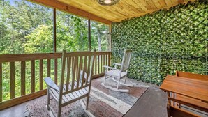 A covered porch with a wooden ceiling, a ceiling fan, a wooden bench, a rocking chair, and a table. - Dreamy Mountaintop Escape for Two | Sauna & Views (Blue Ridge)