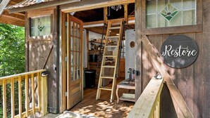 A wooden cabin with a large open door, a ladder, and a sign that reads 'Restore.' - Gilded Hideaway | Romantic Tiny Cabin in the Woods (Blue Ridge)