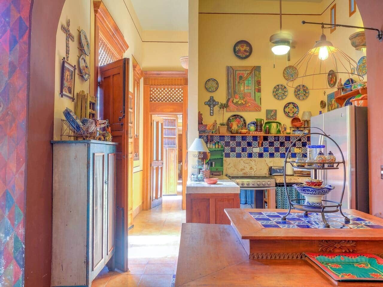 A kitchen with a wooden cabinet, a tiled backsplash, and a hanging light fixture.