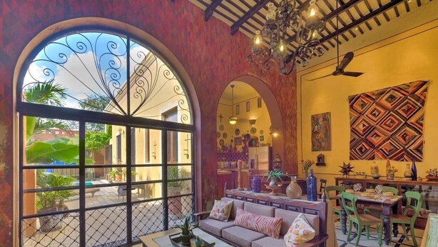 Un'ampia zona giorno con divano, tavolino da caffè e tavolo da pranzo. Grandi finestre ad arco offrono vista sull'esterno.