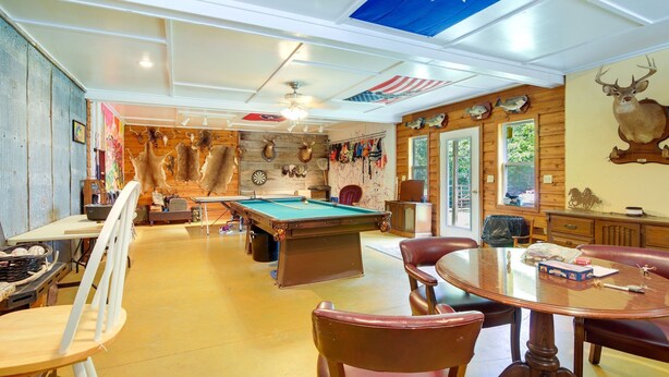 Una habitación con mesa de billar, sillones de cuero, una mesa de comedor y una bandera de Texas.