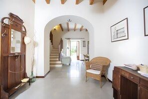 A hallway with a wooden wardrobe, a wicker chair, and a desk with a basket. - Ca sa padrina. tradition and charm in mallorca (Artà)