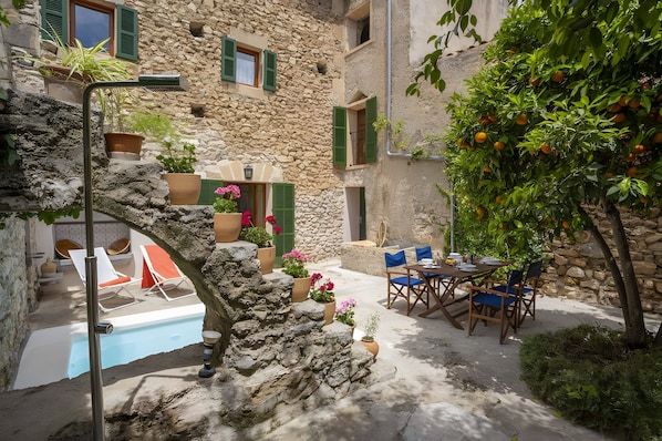 A stone building with a pool, outdoor seating, and potted plants. - Ca sa padrina. tradition and charm in mallorca (Artà)