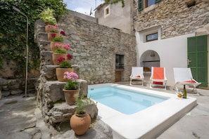 A stone wall with potted plants, a swimming pool, and outdoor seating. - Ca sa padrina. tradition and charm in mallorca (Artà)