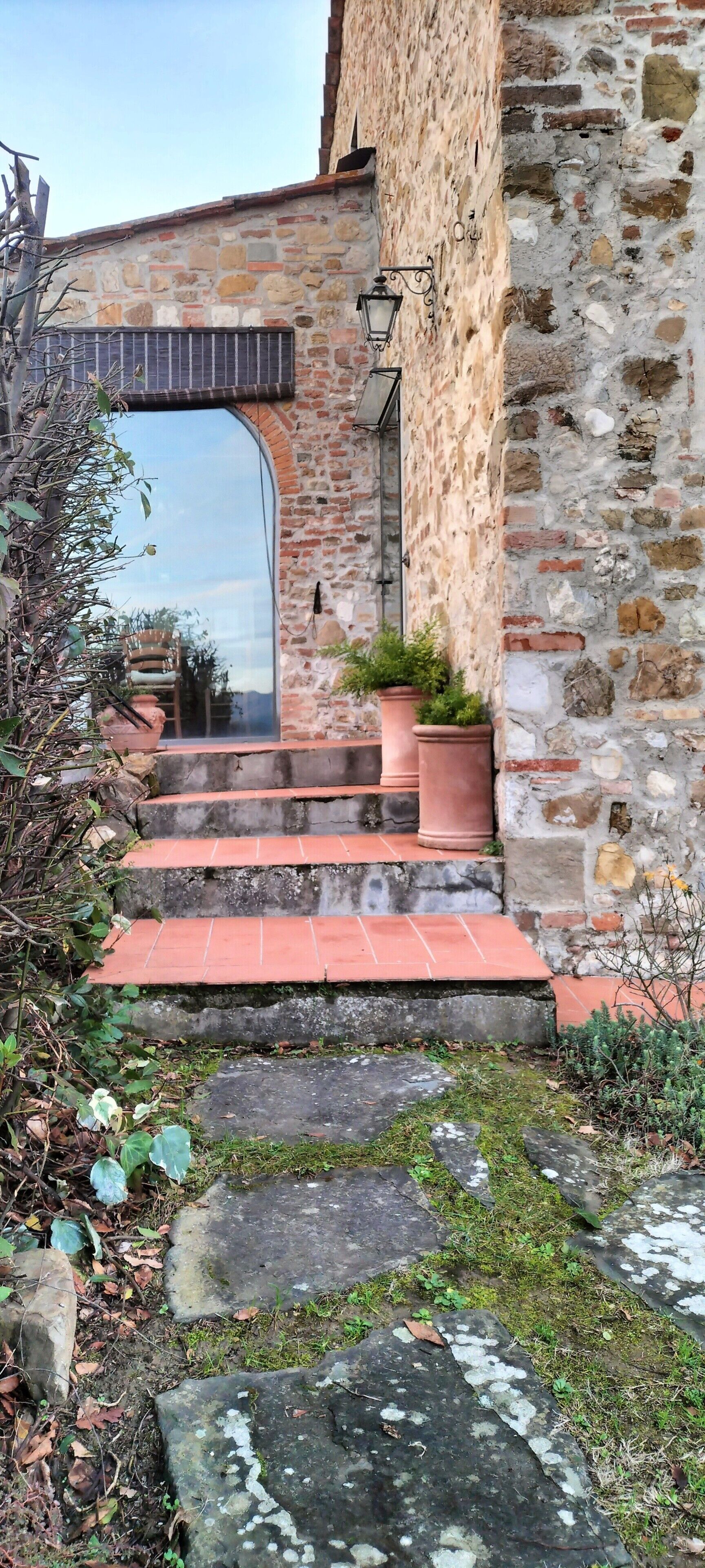 Ein Steinhaus mit Ziegelbogen, Stufen, die zu einer Tür führen, und einer Laterne an der Wand.
