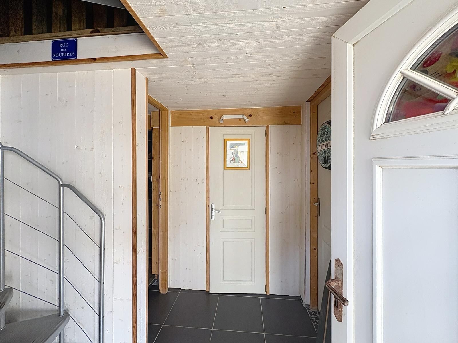 A hallway with a white door, a picture frame, and a sign above the door.
