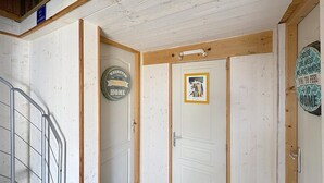 A hallway with a staircase, a door with a framed picture, and a sign on the wall. - 8-BERTH CHALET WITH LARGE TERRACE (Gruissan)