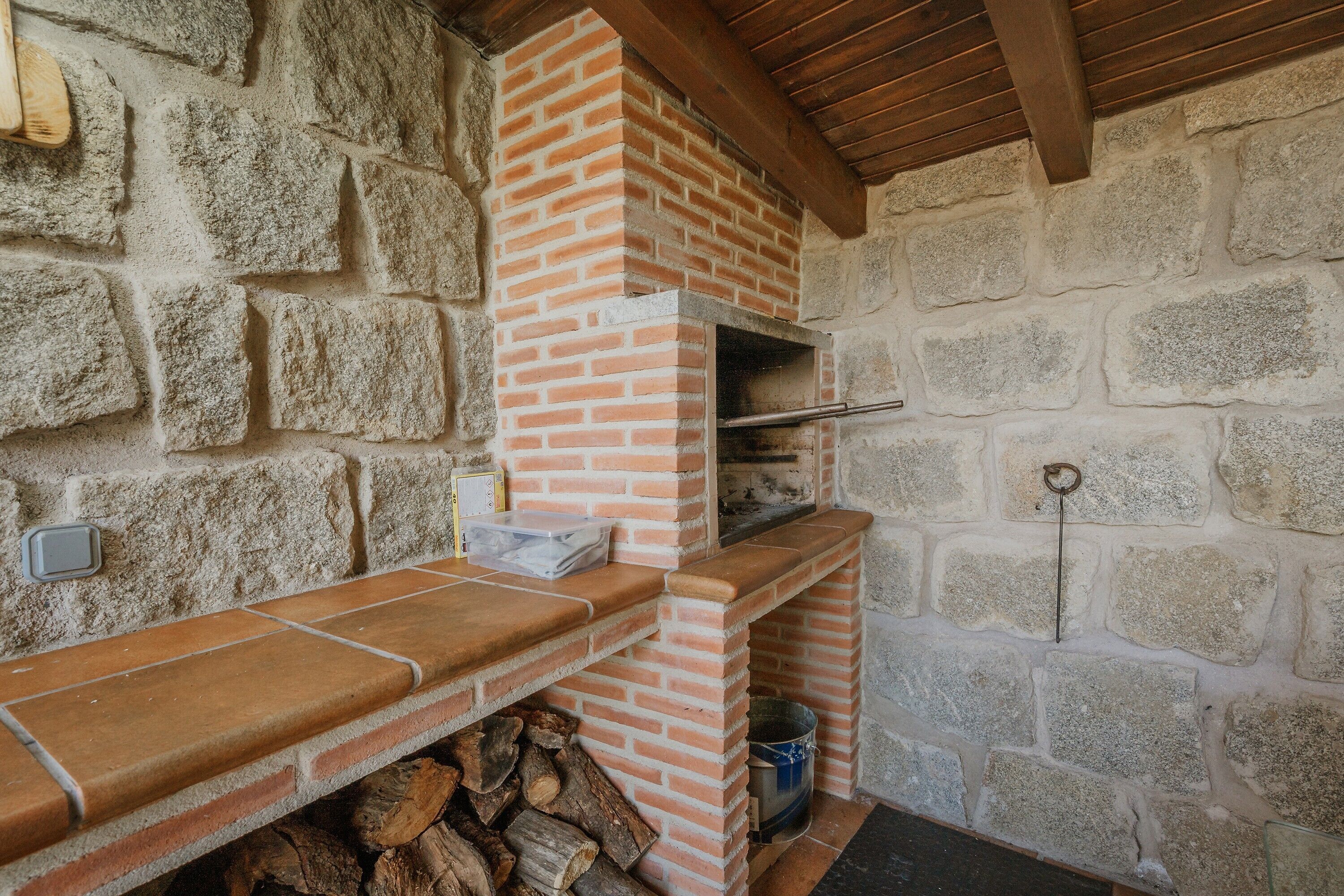 A stone wall with a brick fireplace, a wooden beam ceiling, and a tiled countertop.