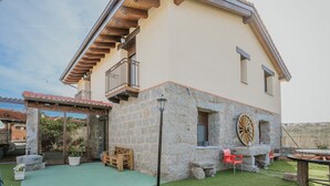 A two-story house with a stone facade, a balcony, and a wooden deck.