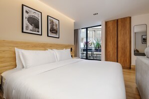 Ein Hotelzimmer mit einem großen Bett, einem Holz-Kopfteil, zwei gerahmten Bildern, einem Holzschrank und einem Balkon mit Pflanzen.