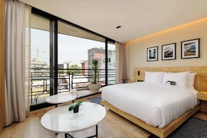 A hotel room with a large bed, a small table, a potted plant, and a balcony with a view of the city. - w* | Airy Loft w/Balcony in Parque Mexico (Ciudad de México)