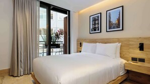A hotel room with a bed, a wooden headboard, a nightstand, a wall-mounted light, and two framed pictures. - w* | Engaging Loft w/ Balcony in Parque Mexico (Ciudad de México)