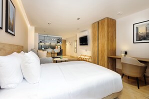 A hotel room with a bed, a desk, a chair, a small table, and a kitchenette in the background. - w* | Stunning Loft in Parque Mexico w/ Balcony (Ciudad de México)
