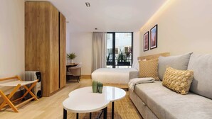A modern hotel room with a sofa, a small round table, a bed, a desk, and a view of the outside. - w* | Engaging Loft w/ Balcony in Parque Mexico (Ciudad de México)