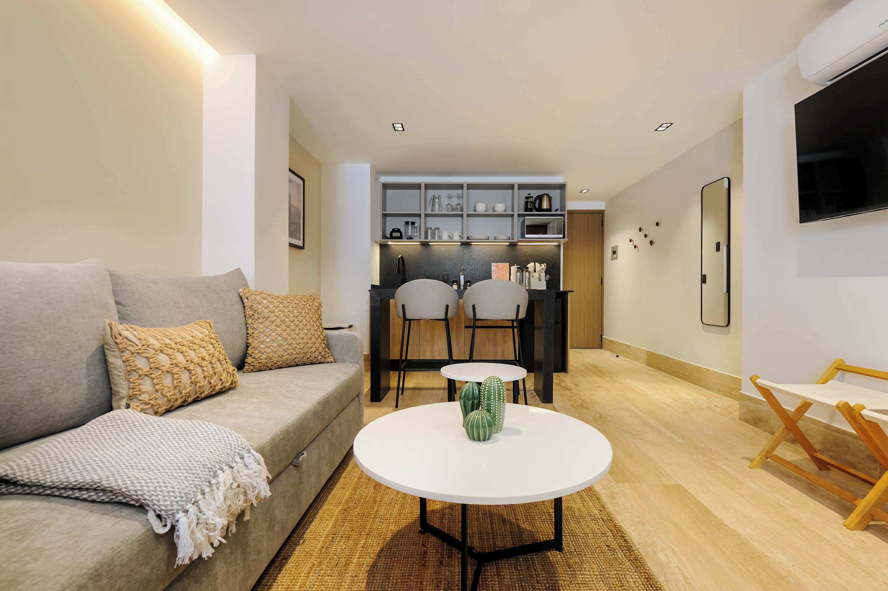 Een moderne woonkamer met een bank, een salontafel en een keuken op de achtergrond.