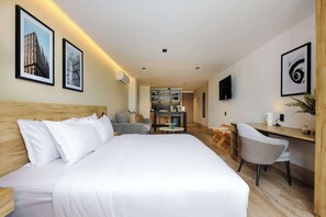 A hotel room with a bed, a desk, a chair, a TV, and a kitchenette in the background. - w* | Urban Loft w/Balcony in Parque Mexico (Ciudad de México)