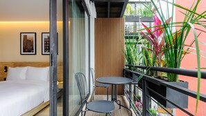 Moderni hotellihuone, jossa on parveke, sänky, pieni pöytä ja tuolit.