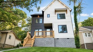 A two-story house with a balcony, a staircase, and a well-maintained lawn. - NEW! The Dwelling Place w/ Rooftop Theater, Fire Pit, Game Room near World Cup (Atlanta)
