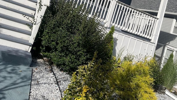 Une maison à deux étages avec un porche, une porte d’entrée ornée d’une guirlande et un petit jardin.