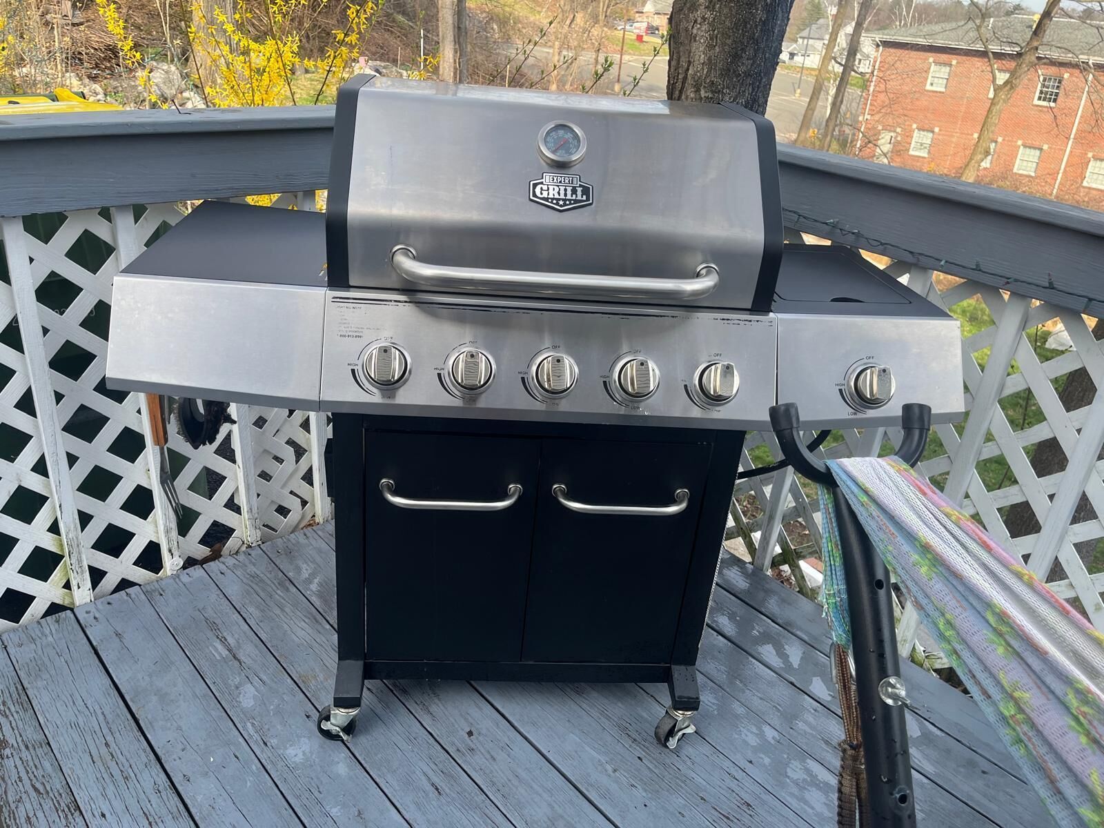 Ein tragbarer Grill mit digitalem Thermometer, vier Kochfeldern und einer Seitablage.