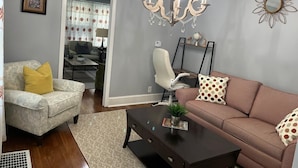 Un salon avec un lustre, un canapé, un fauteuil et une table basse.
