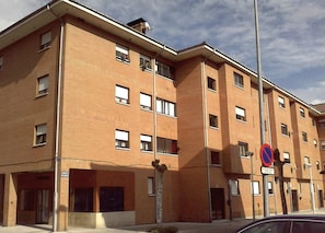 A multi-story brick building with a no parking sign, large windows, and a flat roof. - Apartamento en Calafell Cerca de la Playa (Calafell)