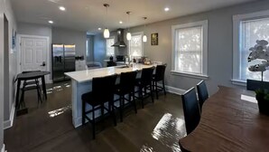 Una cocina moderna con una isla central, taburetes de bar e iluminación colgante.