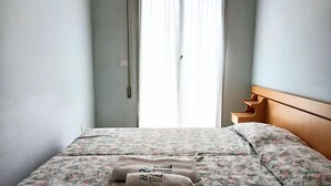 A bed with floral bedding, a wooden headboard, and two towels with text. - RG007 - Bellaria, comfortable three-room apartment 100 meters from the sea (Bellaria-Igea Marina)