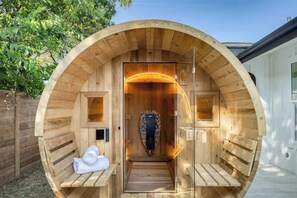A sauna with a wooden exterior, a bench, and a towel. - Wellness Retreat 5BR Villa w/ Pool, Sauna, hot tub (Austin)