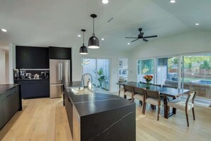 A modern kitchen with a central island, dark cabinetry, and pendant lighting. - Wellness Retreat 5BR Villa w/ Pool, Sauna, hot tub (Austin)
