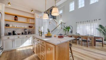 A spacious kitchen with wooden cabinets, a central island, and pendant lighting.