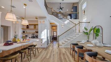 A spacious kitchen with a central island, a staircase, and a dining area with chairs and a table set for a meal.